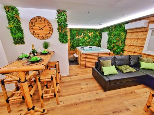 - un salon avec un canapé, une table et un réveil dans l'établissement JUNGLE SPA-4 Pers-Jacuzzi-Parking-Jardin-Clim-Colmar, à Muntzenheim