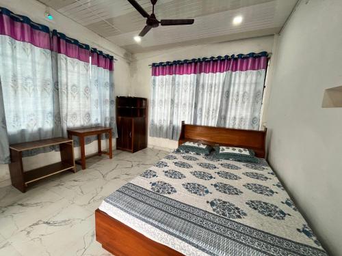 a bedroom with a bed and two windows with curtains at KG Complex Dhuwa Chang Stay in Mohanbāri