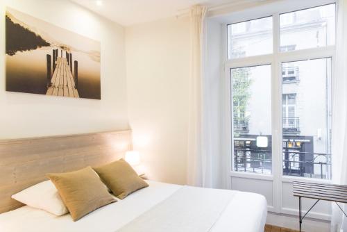 une chambre avec un lit blanc et une fenêtre dans l'établissement Unsejouranantes - Gîte Lamoricière, à Nantes