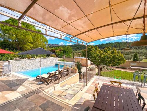an outdoor patio with a pool and an umbrella at Le Panorama des Alpilles in Aureille