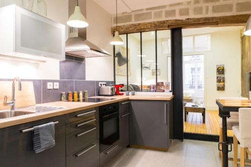 une cuisine avec un évier et une cuisinière four supérieur dans l'établissement Unsejouranantes - Gîte Lamoricière, à Nantes