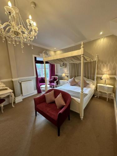 a bedroom with a canopy bed and a red couch at Langtry Manor Hotel in Bournemouth