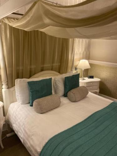 a bedroom with a large bed with green and white pillows at Langtry Manor Hotel in Bournemouth