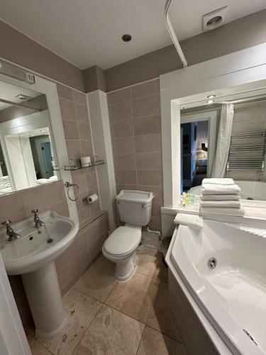 a bathroom with a toilet and a sink and a tub at Langtry Manor Hotel in Bournemouth