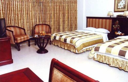 a hotel room with two beds and a chair at Hotel Fortune Garden in Sylhet