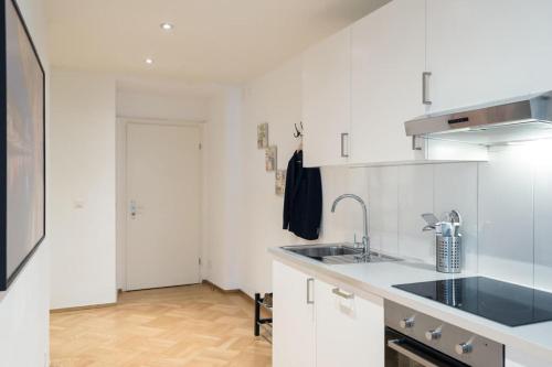 a kitchen with white cabinets and a sink at HITrental Chapel Bridge Apartments in Luzern