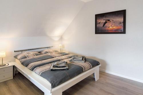 a bedroom with a bed with a picture on the wall at Swaalvkenüst in Moormerland