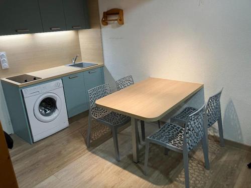 une cuisine avec une table et des chaises ainsi qu'un lave-linge dans l'établissement Appartement vue lac, à Leucate
