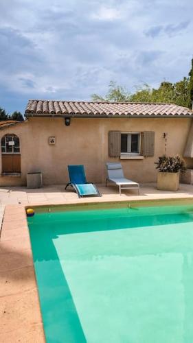 une piscine avec deux chaises bleues et une maison dans l'établissement Maison de campagne avec Piscine, à Pernes-les-Fontaines