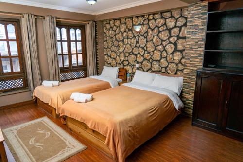 two beds in a room with a stone wall at City Guest House in Bhaktapur