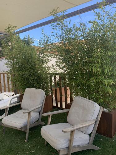 two chairs and a table in a yard at Hôtel Les Sables - Urban Style - by Logis Hotels in Canet-en-Roussillon