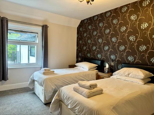 a bedroom with two beds and a wall with a wallpaper at The Half Moon in Petersfield