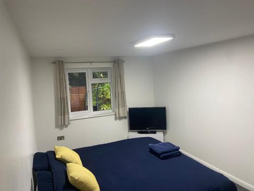 a bedroom with a blue bed and a television at Wyndham studio in Uphill