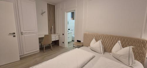 a bedroom with a white bed with pillows and a desk at Anita's Mansion in Gattendorf