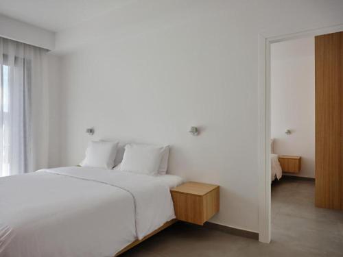 a white bedroom with a large bed and a mirror at Villa Christy in Psarou