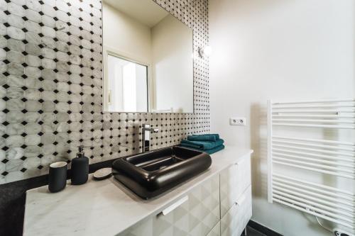 une salle de bain avec un lavabo noir et un miroir dans l'établissement Joli Hotel Particulier proche du jardin du Luxembourg, à Paris