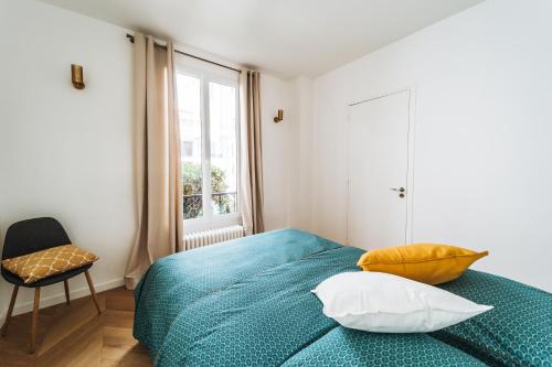 - une chambre avec un lit bleu et des oreillers jaunes dans l'établissement Joli Hotel Particulier proche du jardin du Luxembourg, à Paris