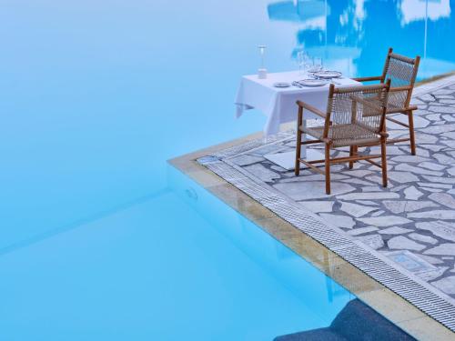a table and two chairs next to a swimming pool at Atlantica Nissaki Beach - Adults Only in Gimari