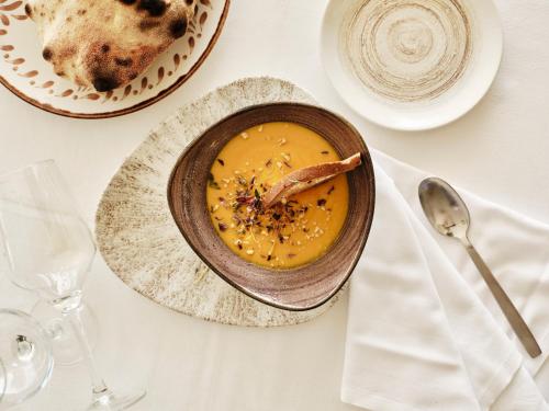 a bowl of soup on a table with a plate of food at Atlantica Nissaki Beach - Adults Only in Gimari