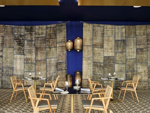 a room with tables and chairs and a blue wall at Atlantica Nissaki Beach - Adults Only in Gimari