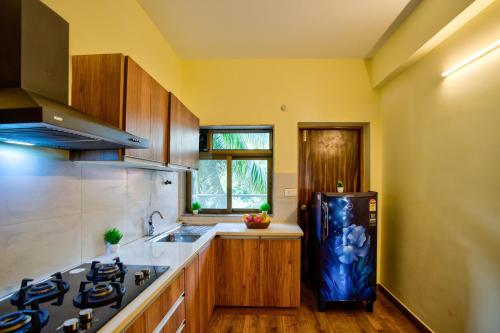 a kitchen with a black refrigerator and wooden cabinets at Luxury 2BHK Apartment Near Candolim in Nerul