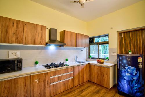 a kitchen with wooden cabinets and a blue refrigerator at Luxury 2BHK Apartment Near Candolim in Nerul