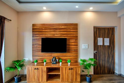 a living room with a tv and a wooden wall at Luxury 2BHK Apartment Near Candolim in Nerul