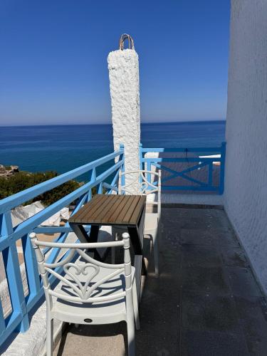 a table and chairs on a balcony with the ocean at The Rocas Hotel in Kérynia
