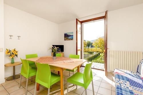 a dining room with a table and green chairs at Budget Village Apartments - Porto Letizia in Porlezza