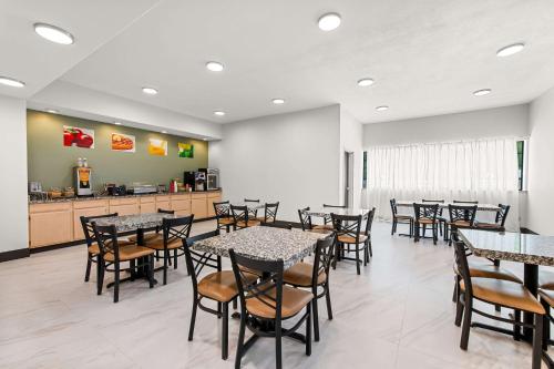 a dining room with tables and chairs and a kitchen at Quality Inn & Suites Kilgore-Longview in Kilgore