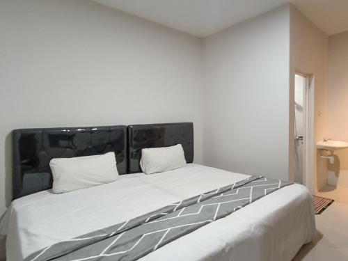 Happy Family Homestay Jember Mitra RedDoorz في جيمبر: سرير أبيض كبير ووسادتين عليه