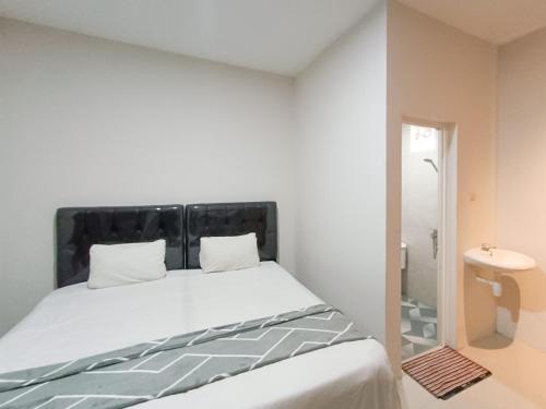 Happy Family Homestay Jember Mitra RedDoorz في جيمبر: غرفة نوم مع سرير مع اللوح الأمامي الأسود