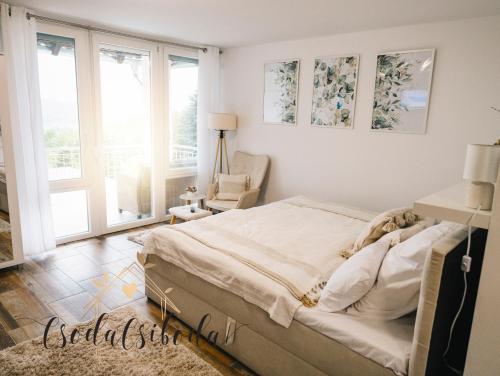 a bedroom with a bed and a chair and windows at CsodaCsiboda in Lentihegy