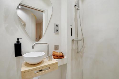 une salle de bain avec un lavabo et un miroir dans l'établissement Le petit luxe parisien, à Paris
