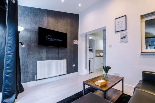 a living room with a couch and a tv on a wall at Sleeps 7, Games Room, Perfect For Groups, Driveway, Smart TV, Available For Long Stays in Manchester