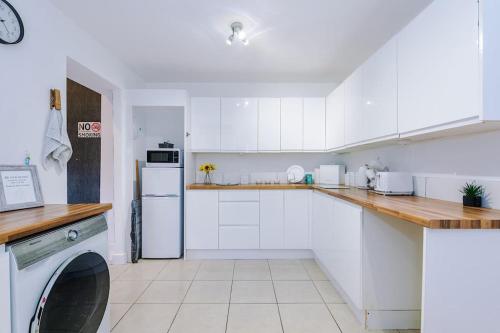 a kitchen with white cabinets and a white refrigerator at Sleeps 7, Games Room, Perfect For Groups, Driveway, Smart TV, Available For Long Stays in Manchester