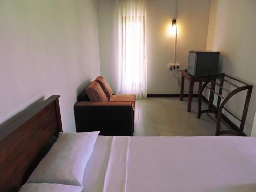 a bedroom with a bed and a couch and a television at Green Sapphire Holiday Resort Wilpaththu in Wilpattu