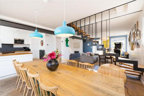 une salle à manger et un salon avec une grande table en bois dans l'établissement la Villa du Thar - plage 300m piscine babyfoot arcade pingpong pétanque, à Saint-Pair-sur-Mer