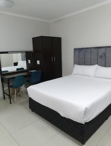 a bedroom with a large white bed and a desk at Bayside Hotel Suites in Durban