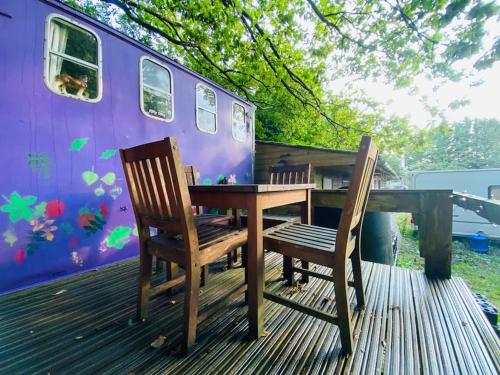 a table and two chairs on a deck with a trailer at Camp Hillcrest Horsebox in Lydney