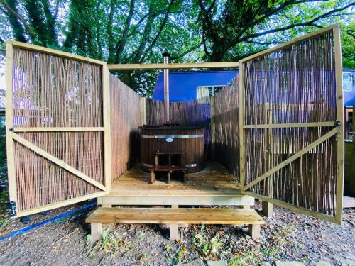 a wooden privacy fence with a bench in front of a tree at Camp Hillcrest Horsebox in Lydney