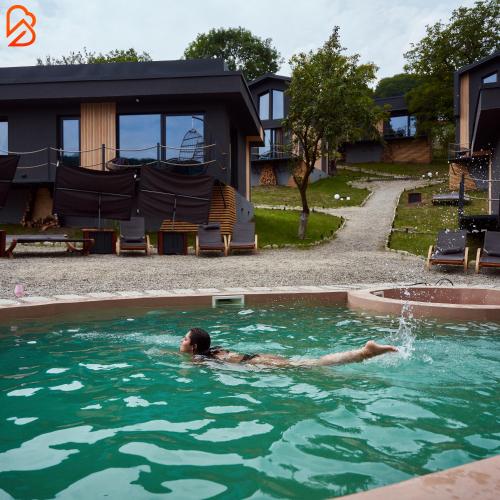a man is swimming in a swimming pool at Blissful Resort - Valea Doftanei in Teşila