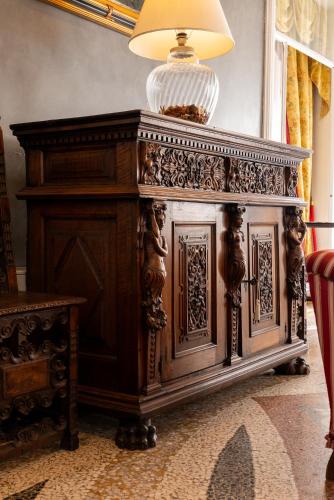 a wooden cabinet in a room with a lamp on top at Hotel Villa Borghi in Varano Borghi