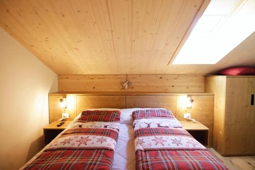 two beds in a room with a roof at SKYWAY LOFT - Agenzia Dolomiti Affitti in Cavalese