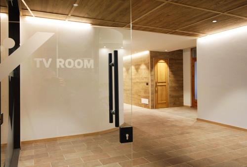 a glass wall in a lobby with a tv room at SKYWAY LOFT - Agenzia Dolomiti Affitti in Cavalese