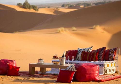a table with red and blue pillows in the desert at Royal Sands Camp in Merzouga