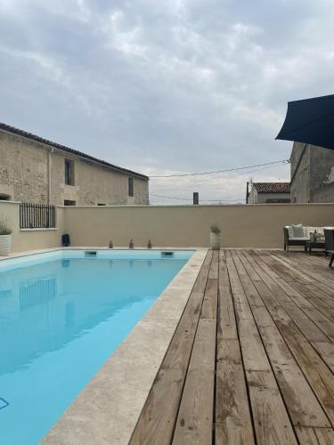 une piscine avec une terrasse en bois et un parasol dans l'établissement Plemont, à Saint-Sulpice-de-Cognac