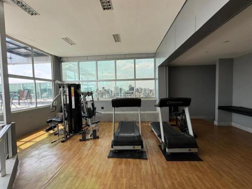 a gym with cardio equipment in a large room with windows at San Diego Apart- Hotel in Belo Horizonte