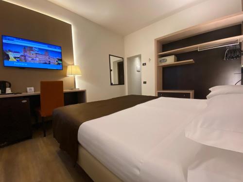 a hotel room with a large bed and a tv at Hotel Carlton in Ferrara
