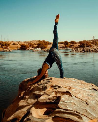 a person doing a handstand on a rock in the water at Dolty Kato Nubian House By Kato Dool in Aswan